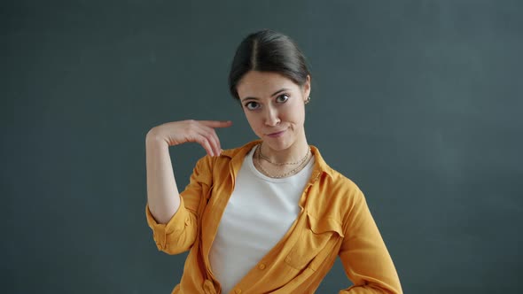 Portrait of Female Student Twisting Finger at Head Making Fool Sign Looking at Camera