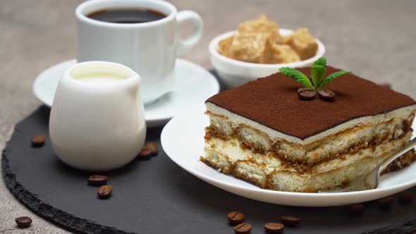 Portion of Traditional Italian Tiramisu dessert, cup of espresso and cream or milk