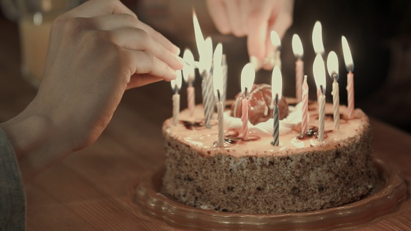 Two People Lighting the Candels on A Birthday Cake