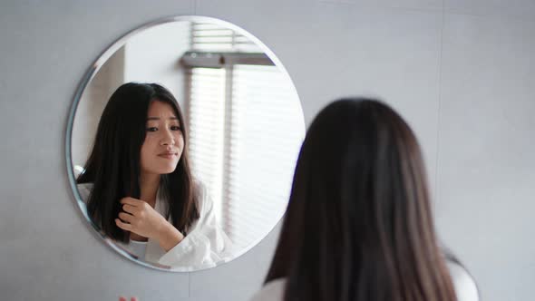 Asian Woman Touching Hair Having Split Ends Problem In Bathroom