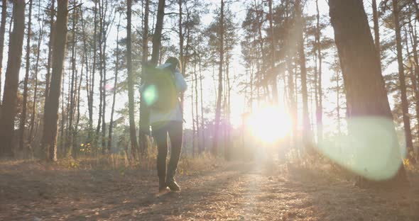 Young attractive woman tourist in blue jacket with big tourist backpack walking in fall forest