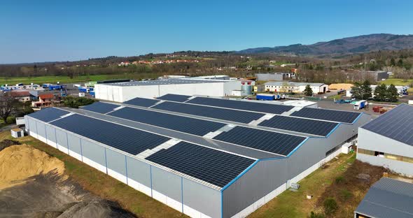 Aerial View of Blue Photovoltaic Solar Panels Mounted on Industrial Building Roof for Producing