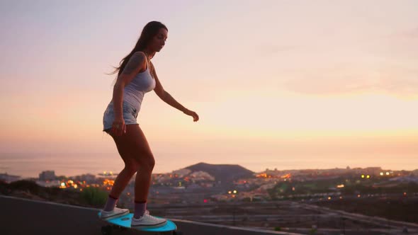 Girl Riding a Skateboard Near the Ocean and a Large Mountain in Slow Motion. Healthy Lifestyle