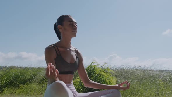 Young African Woman in Lotus Yoga Position Sitting Outdoors Near the River