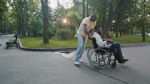 Mature Adult Black Man Walking in Summer Park with Paralyzed Nonmobile African Guy Men Having Fun on