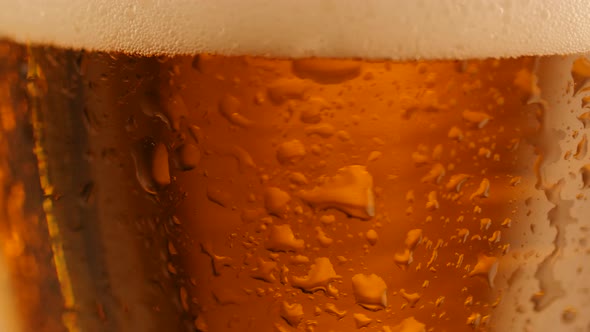 Detail Shot of Rotating Fresh Beer with Drops on Glass