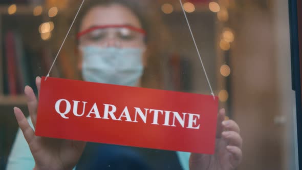 Closeup of Female Owner in Safety Mask and Goggles Holding Quarantine Sign in Clothing Store