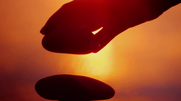 A Hand Lays a Stone on Top of a Tower of Stones. Harmony and Balance Concept