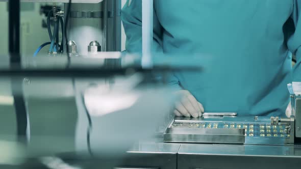 Pharmaceutics Worker Is Controlling a Conveyor with Pills