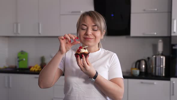 Happy Female Eating Cherry From Cake in Kitchen