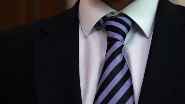 Man in suit tying a tie. Businessman in black suit tying the necktie.