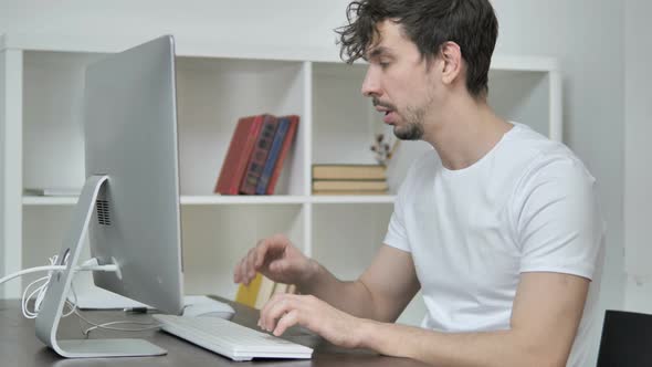 Sick Young Man Coughing and Working on Desktop