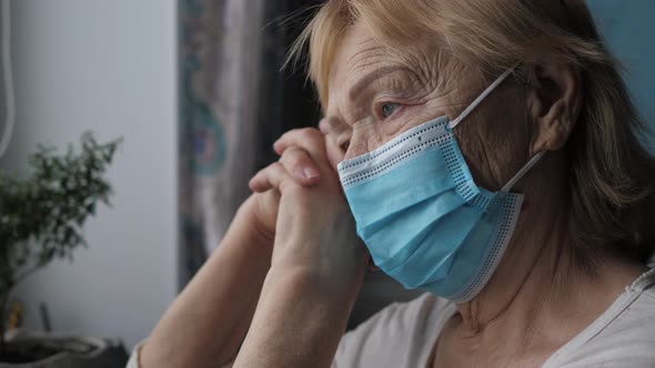 Sadness Elderly Old Woman In Protective Mask Looks Out Window