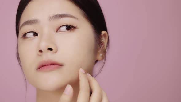 Close up face of young Asian woman worry about face skin problem on pink background.