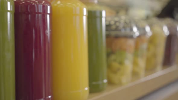 Close-up Row of Fresh Juices and Colorful Dried Fruits on the Store Shelf. Camera Moving Along Goods