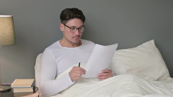 Hardworking Middle Aged Man Reading Documents in Bed 