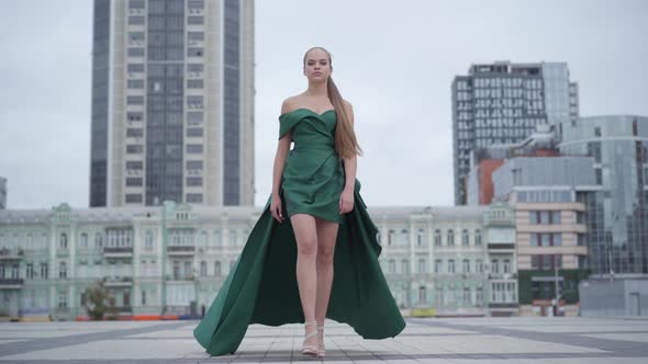 Beautiful Gorgeous Girl in a Stunning Evening Green Dress Walking Fascinatingly on Empty City Square
