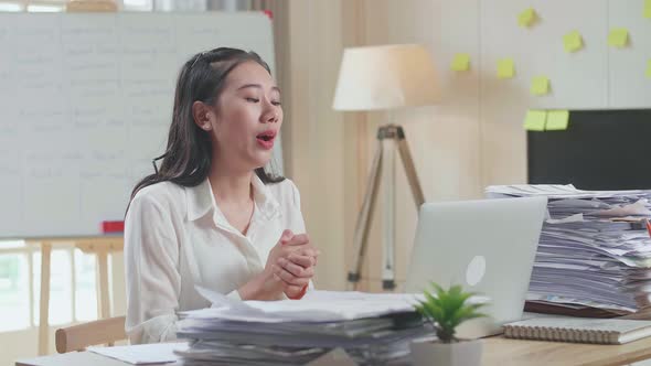 Asian Woman Having Video Call On Laptop While Working With Documents At The Office