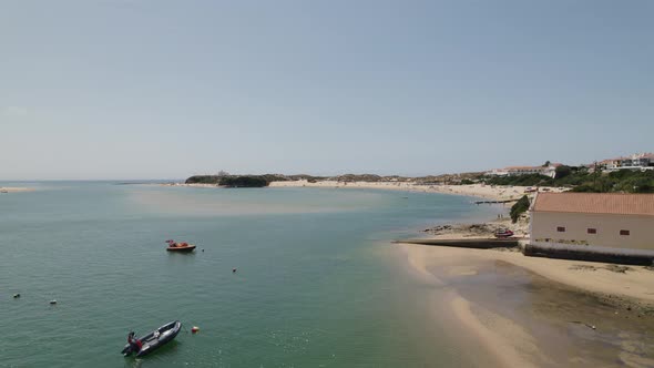 Aerial Flying Over Boats Floating Mira River With View Of Praia da Franquia At Vila Nova de Milfonte