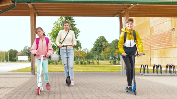 Happy School Children with Mother Riding Scooters