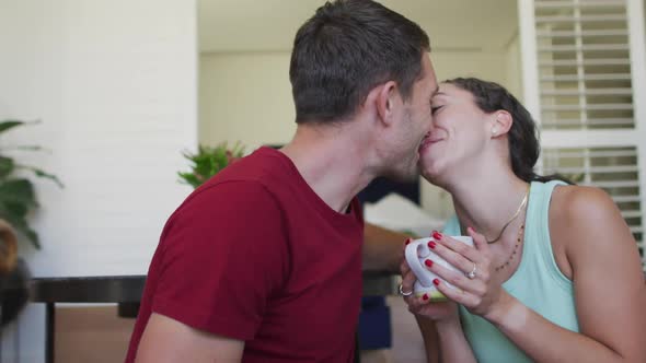 Happy caucasian couple in love drinking coffee and kissing