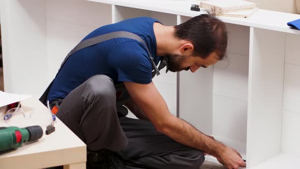 Male Worker in Coverall Screwing a Bolt for Furniture Assembly