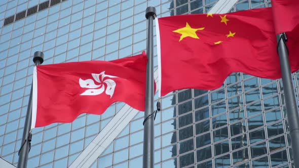 Hong Kong Flag and China Flag Waving On A Skyscraper Building