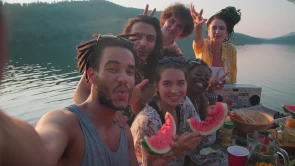 Happy Friends Posing for Camera and Taking Selfie at Lake Party