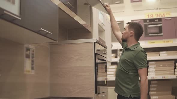 a Young Man Examines the Kitchen Rack in the Mall He Wants to Buy It