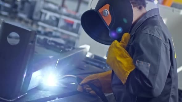 Black Female Welder Putting on Mask and Starts Welding