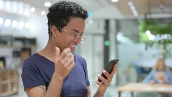 Portrait of Casual African Woman Celebrating Success on Smartphone 
