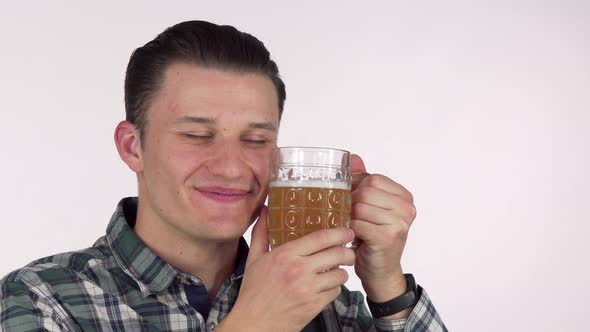 Happy Young Man Smiling with Eyes Closed, Cuddling with a Mug of Tasty Beer