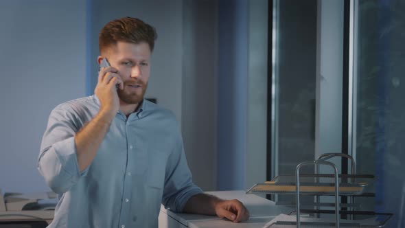 Successful Male Entrepreneur Making Phone Call at Office By Window