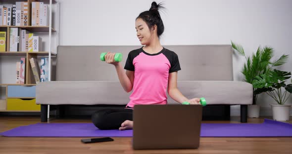 Woman looking laptop and training dumbbells