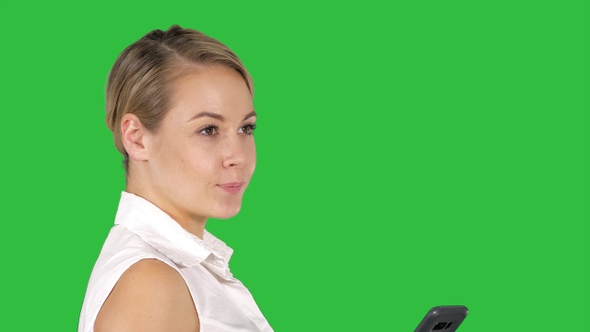 Young beautiful woman writes an SMS on a Green Screen, Chroma Key.