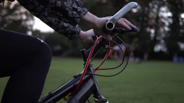 Female hands on bicycle in the park medium shot slow tilting shot