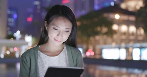 Woman Holding Tablet Computer in City at Night