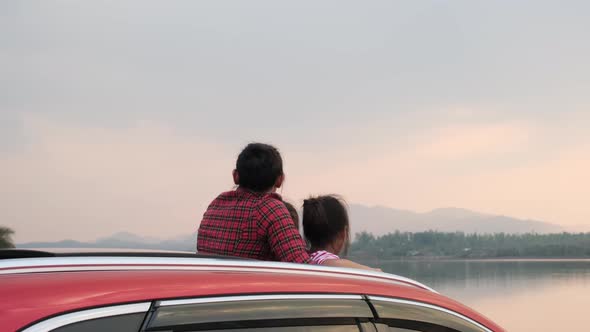 Mother and child enjoying nature along the way in the car on sunroof.