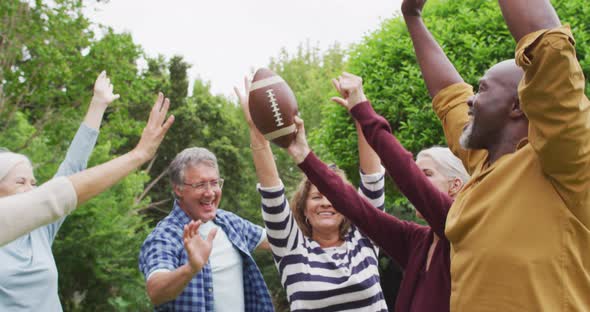 Animation of happy diverse female and male senior friends playing american football in garden