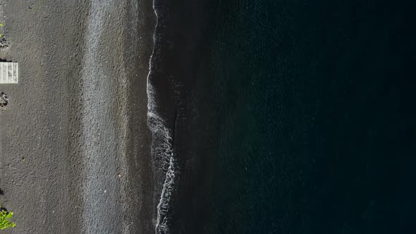 Top down view on waves on black sand beach