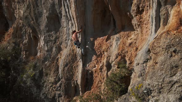 Slow Motion Aerial Drone Footage of Strong Man Rockclimber Climbing Up on Tough Hard Route on