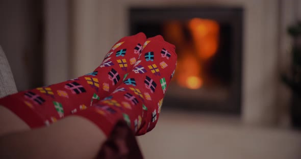 Woman Wearing Warm Wool Socks Lying By the Fireplace at Christmas