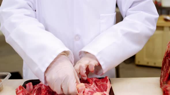 Female butcher arranging raw meat in a tray