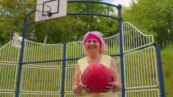 Senior Woman Grandmother Athlete Posing Playing with Ball Outdoors on Basketball Playground Court