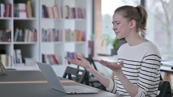 Upset Young Woman Reacting to Loss on Laptop in Library