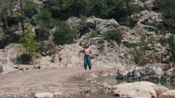 A Woman in Wide Pants Doing Simple Gymnastics on Nature