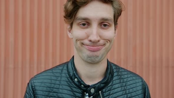 Slow Motion Portrait of Funny Guy Student Grimacing Having Fun Outdoors Against Wall Background