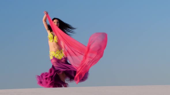 Girl with a Veil in Her Hands Dances a Belly Dance in the Desert