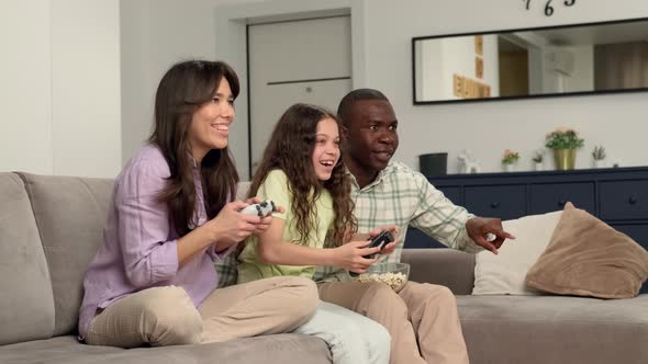 Multi Ethnic Family Playing Video Game at Home Sitting on Sofa