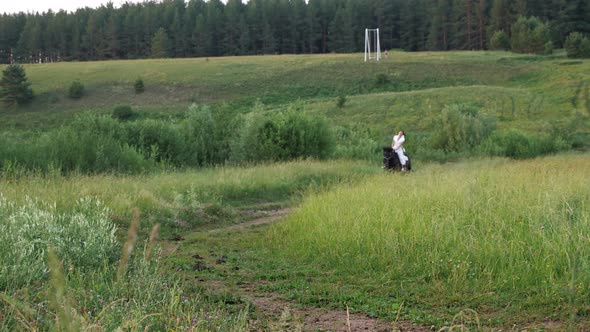 Lady Rider in White Dress Gallops Stallion Along Ground Road